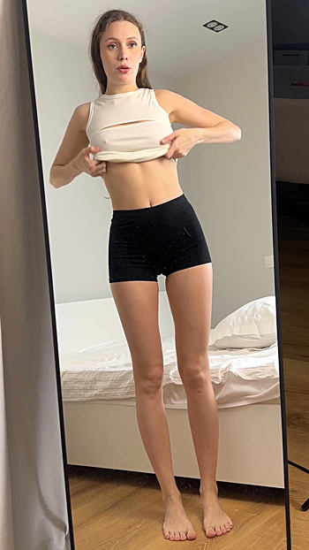 Slender woman undresses beautifully in front of a mirror